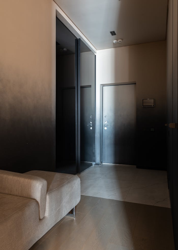 Comfortable couch and big wardrobe with glass mirrored doors in spacious corridor of modern apartment